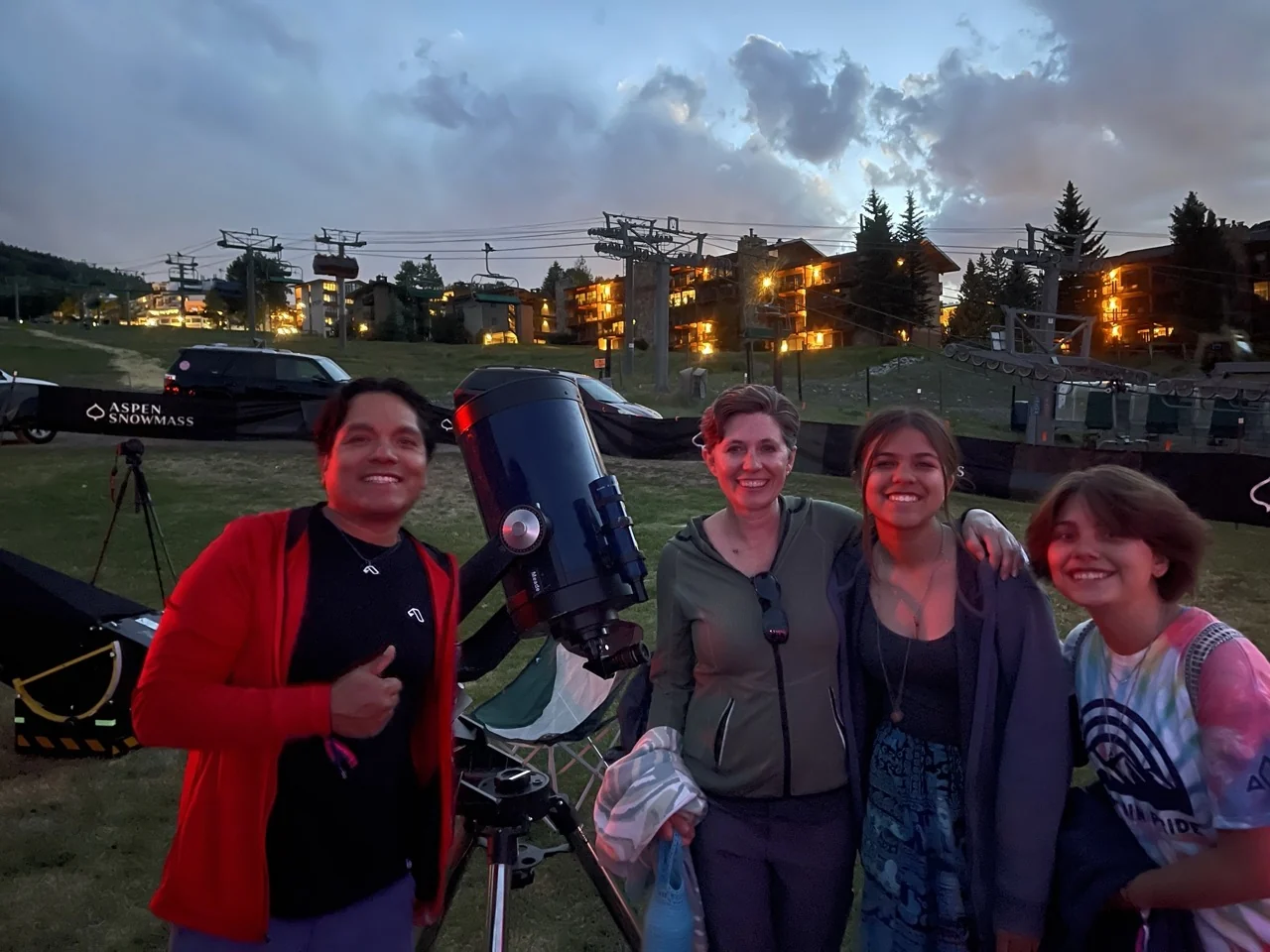 A group smiling beside an AstroTours telescope at an evening program